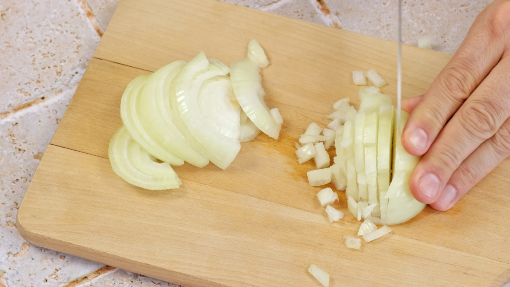 Eine helle Zwiebel wird in Würfel geschnitten.