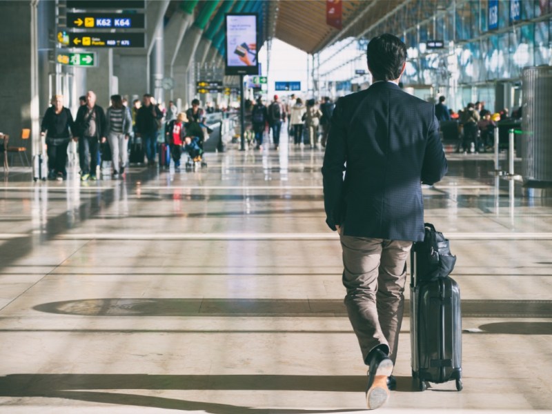 Ein Geschäftsmann mit einem Koffer an einem Flughafen.