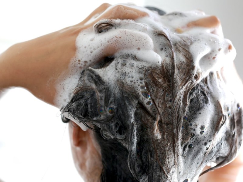 Eine Person schäumt seine Haare mit Shampoo ein.