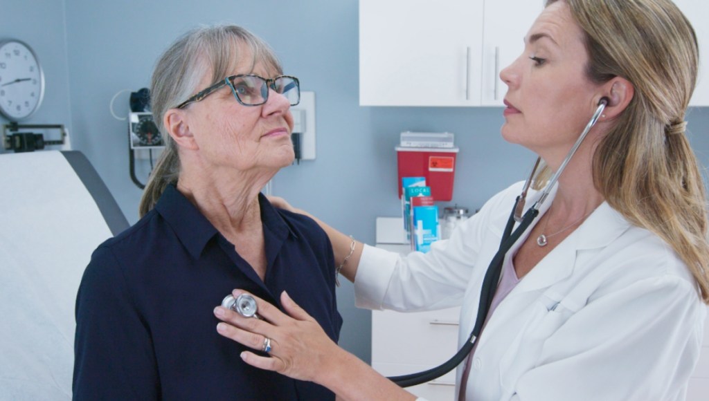 Eine junge Ärztin hört mit einem Stethoskop eine ältere Patientin ab.