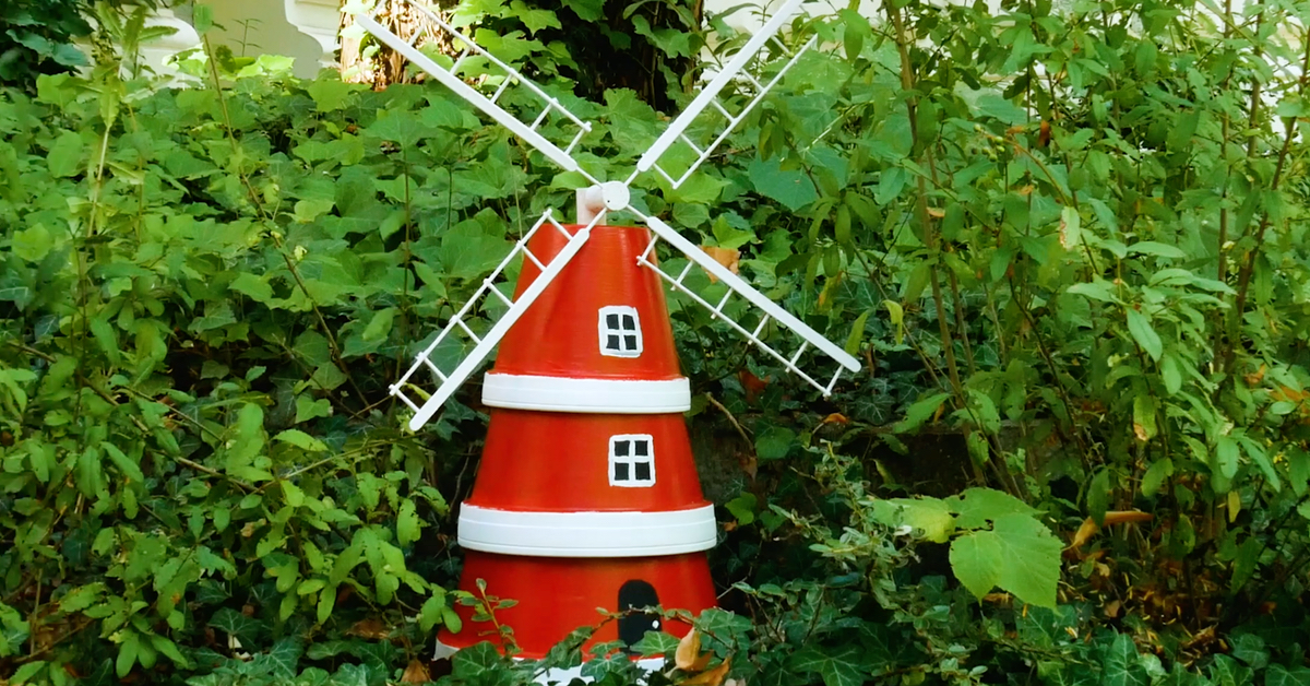 Eine Deko-WindmÃ¼hle, aus BlumentÃ¶pfen gebastelt, steht in einem Garten.