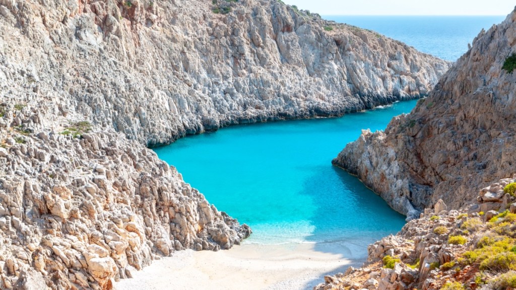 Ein traumhafter Strand zwischen Felsen mit azurblauem Wasser.