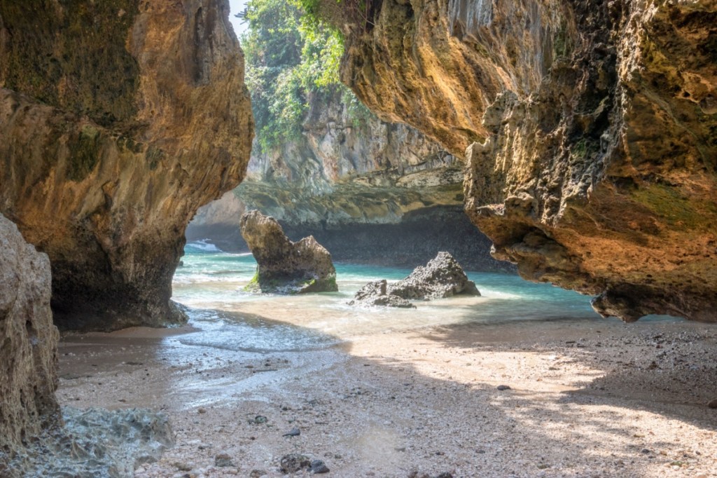 Ein indonesischer Strand in einer felsigen Bucht.