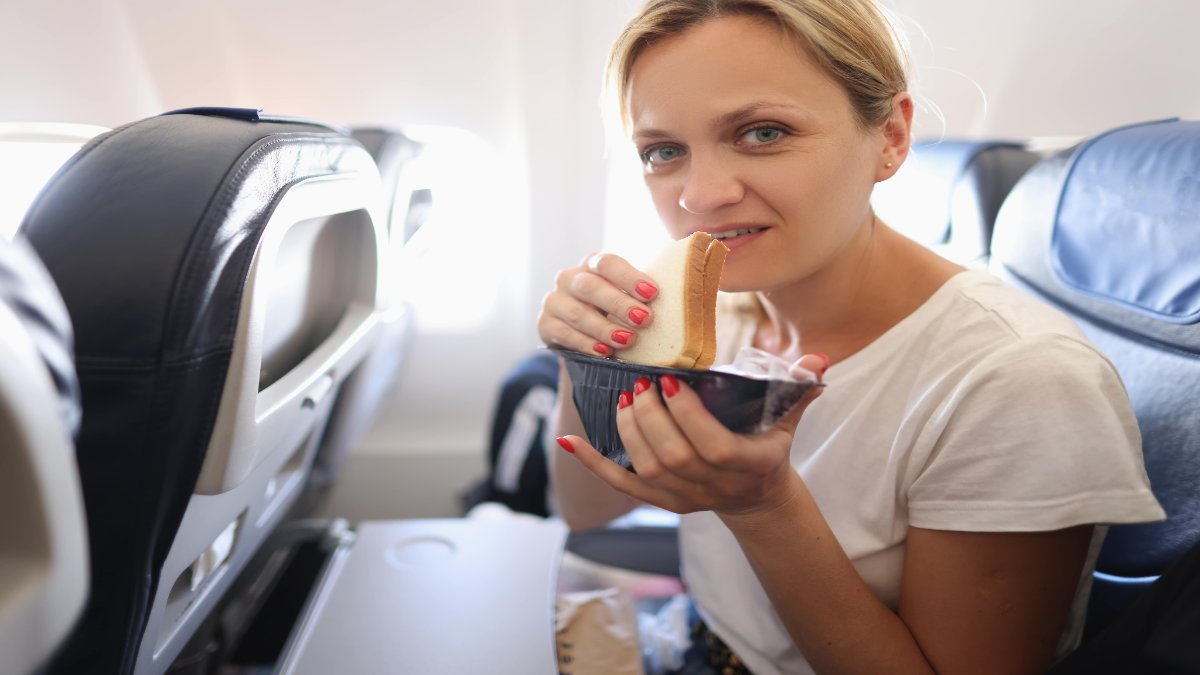 Frau guck fragend in die Kamera wÃ¤hrend sie ein Sandwich isst.