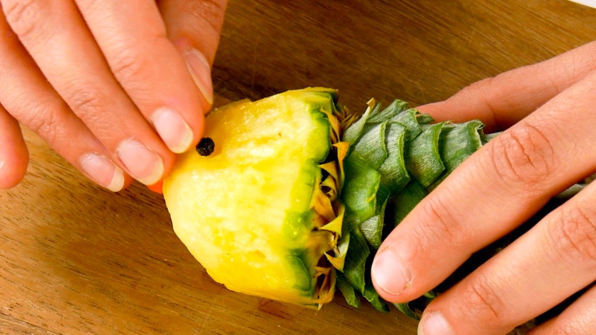 Pfefferkorn wird in Fruchtfleisch von Ananas gedrückt
