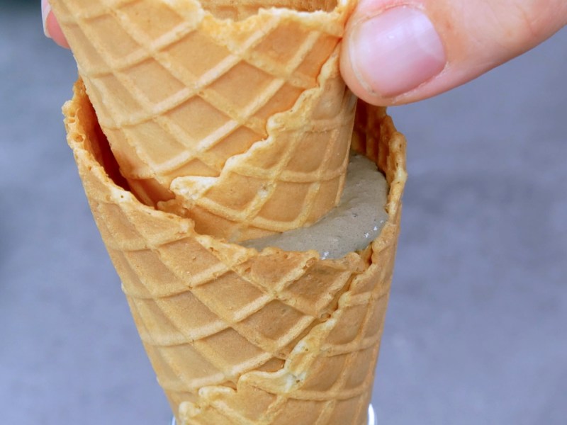 Jemand steckt eine Eiswaffel in eine Eiswaffel, in der Zement angemischt wurde