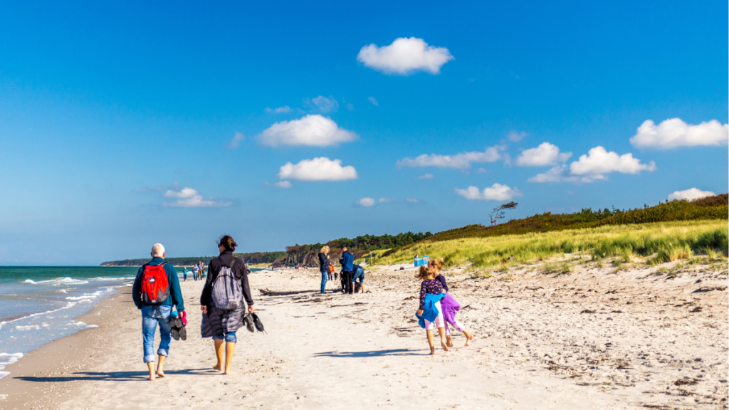 Verschiedene Menschen, die am Strand spazieren gehen.