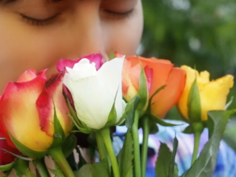 Eine junge Frau riecht an einem Strauß Rosen.