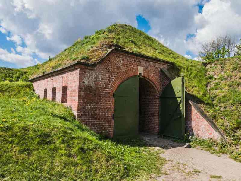 Ein mit Gras bewachsener Bunker aus Ziegelsteinen unter einem HÃ¼gel.