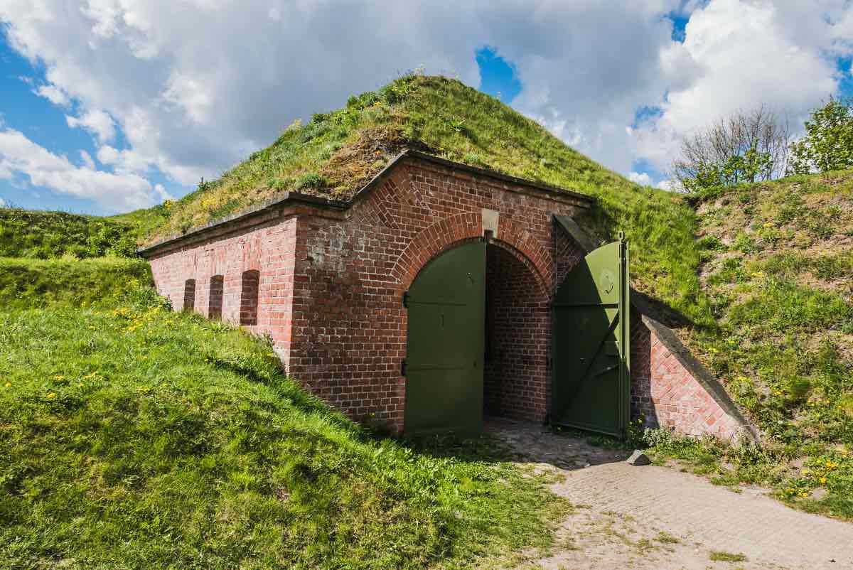 Ein mit Gras bewachsener Bunker aus Ziegelsteinen unter einem HÃ¼gel.