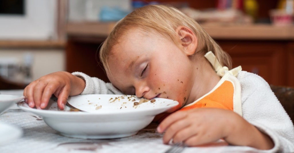 Mädchen ist nach dem Essen am Tisch eingeschlafen