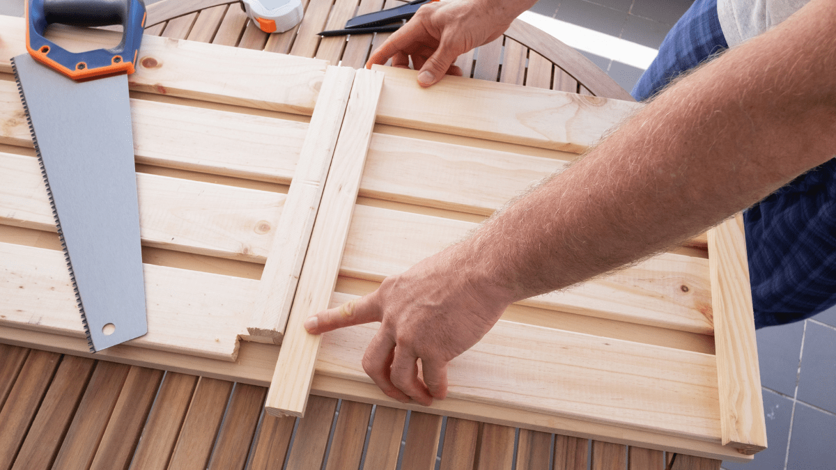 Mann baut etwas aus Holz auf einem Balkon