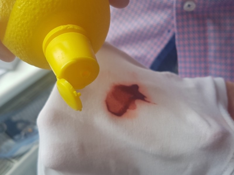 Ein Mann ist dabei, Blutflecken auf einem Hemd zu entfernen mit Zitronensaft aus einer Plastikflasche.