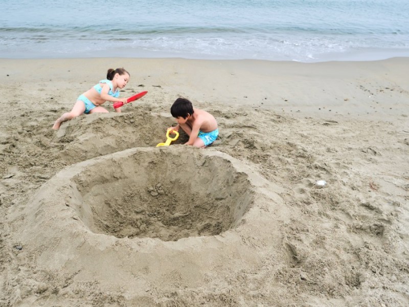 zwei Kinder bauen alleine eine große Sandburg am Strand