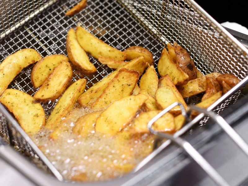 Kartoffelspalten werden in einer Fritteuse frittiert