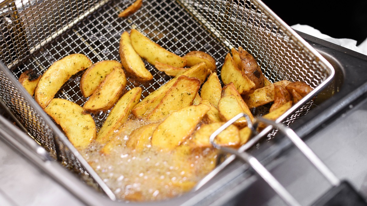 Kartoffelspalten werden in einer Fritteuse frittiert