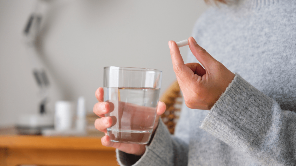 Eine Frau nimmt eine Tablette mit einem Glas Wasser.