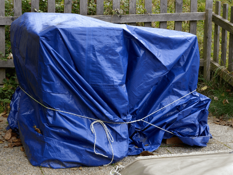 Gartenmöbel, die in blaue Plane eingepackt sind.