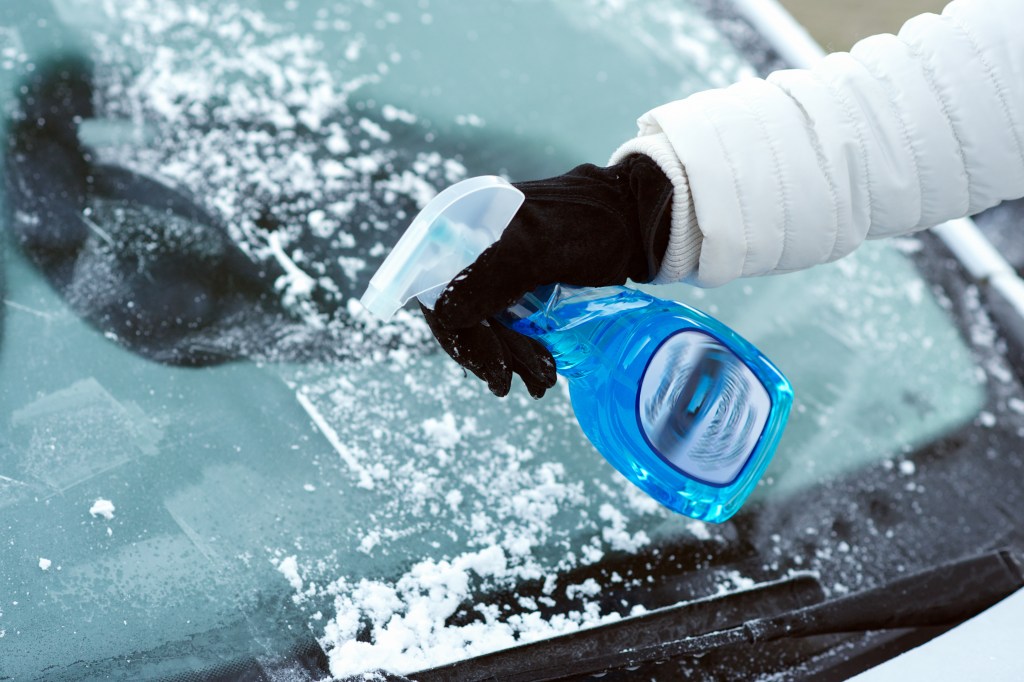 Gefrorene Autoscheibe mit Enteiser-Spray freibekommen.