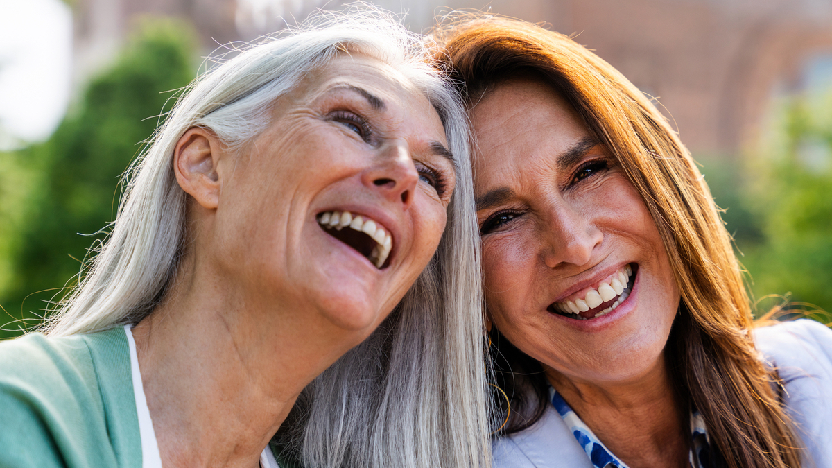 Zwei Frauen über fünfzig lachen miteinander.