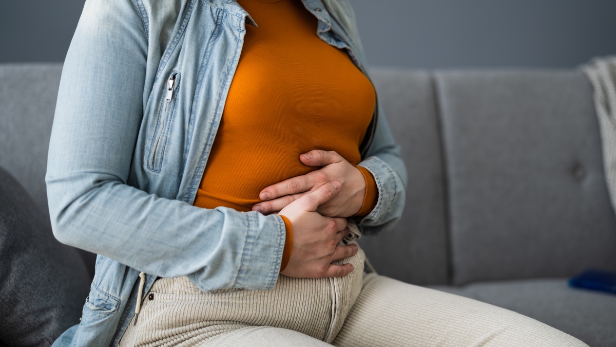 Eine Frau hält sich den Bauch.