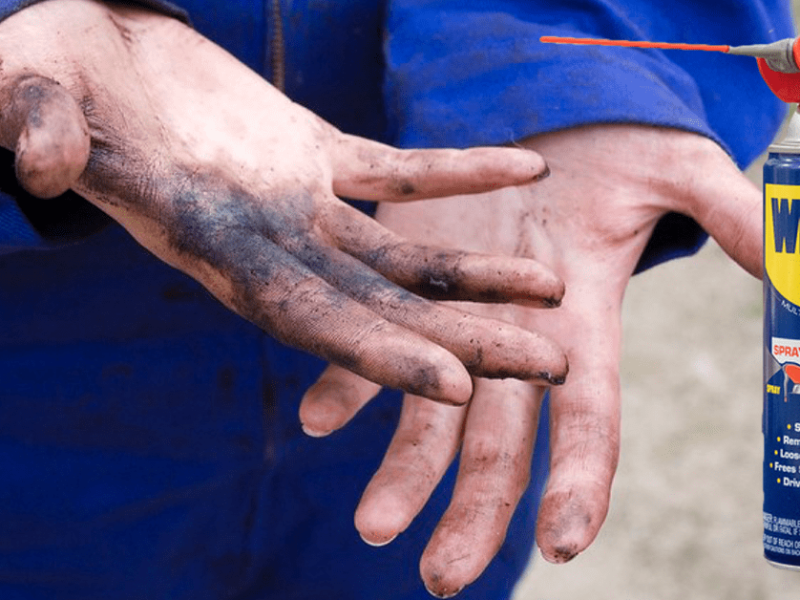 Verschmierte Hände, daneben eine Flasche WD-40