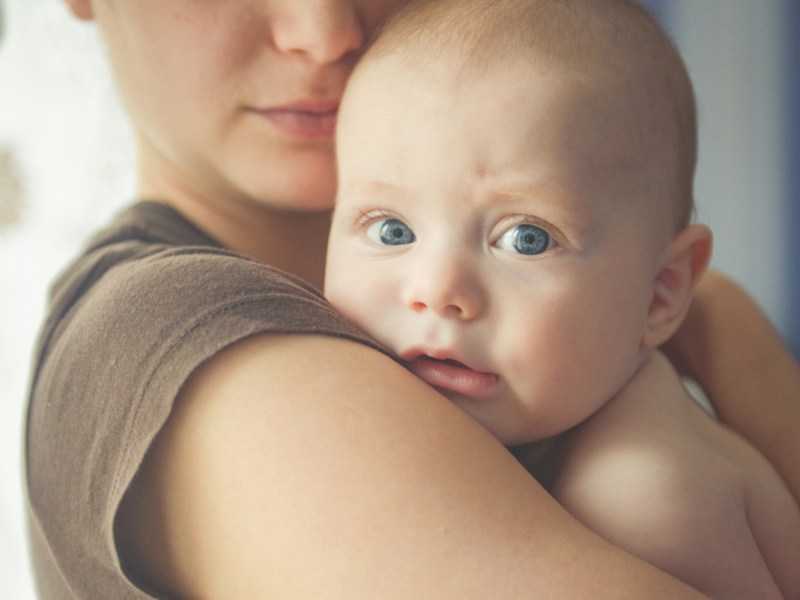 Eine Mutter hält ihr neugeborenes Baby im Arm.