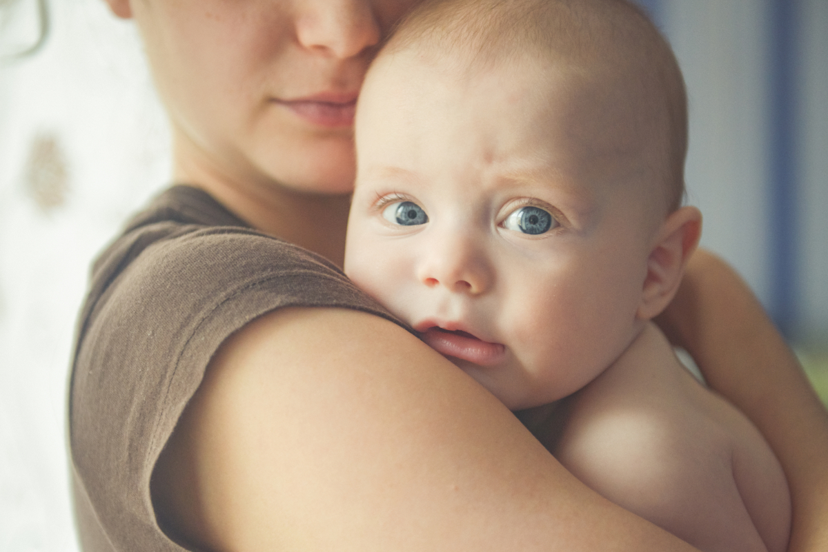 Eine Mutter hält ihr neugeborenes Baby im Arm.