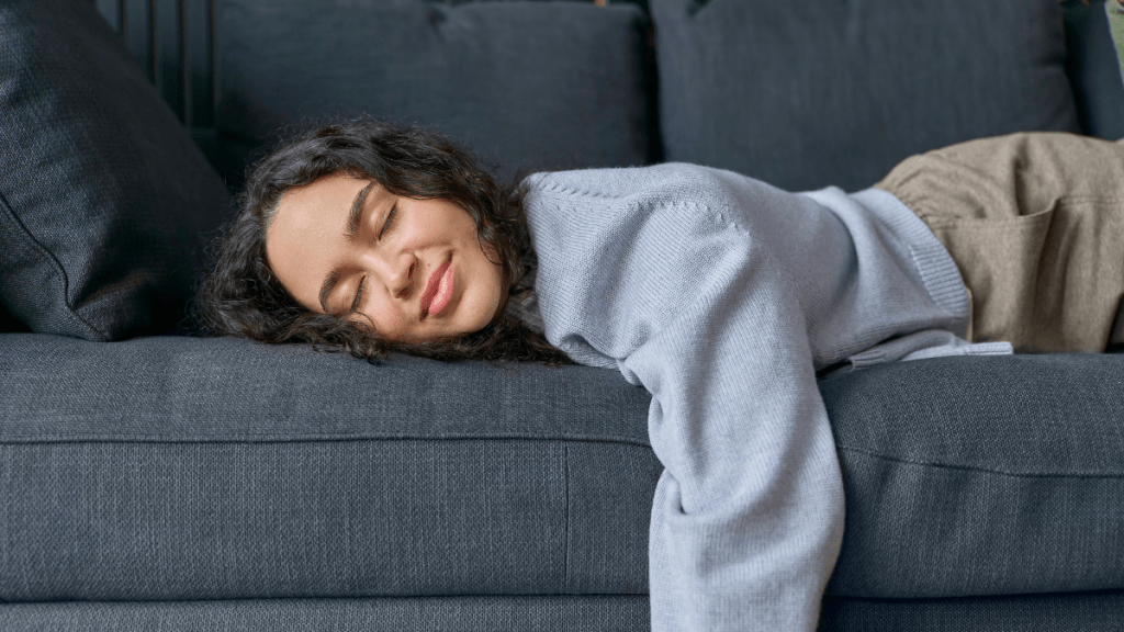 Eine Frau liegt in Bauchlage auf einem Sofa.