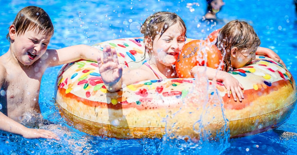 Kinder im Freibad mit Schwimmring und Schwimmflügeln.