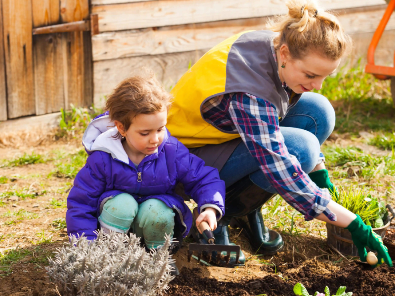 Mutter und Tochter machen Gartenarbeit mit Handschuhen.