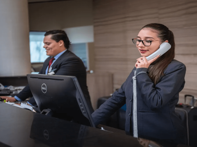 Hotelmitarbeiterin telefoniert in der Rezeption.