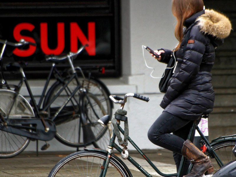 Eine Radfahrerin mit dem Handy in der Hand.