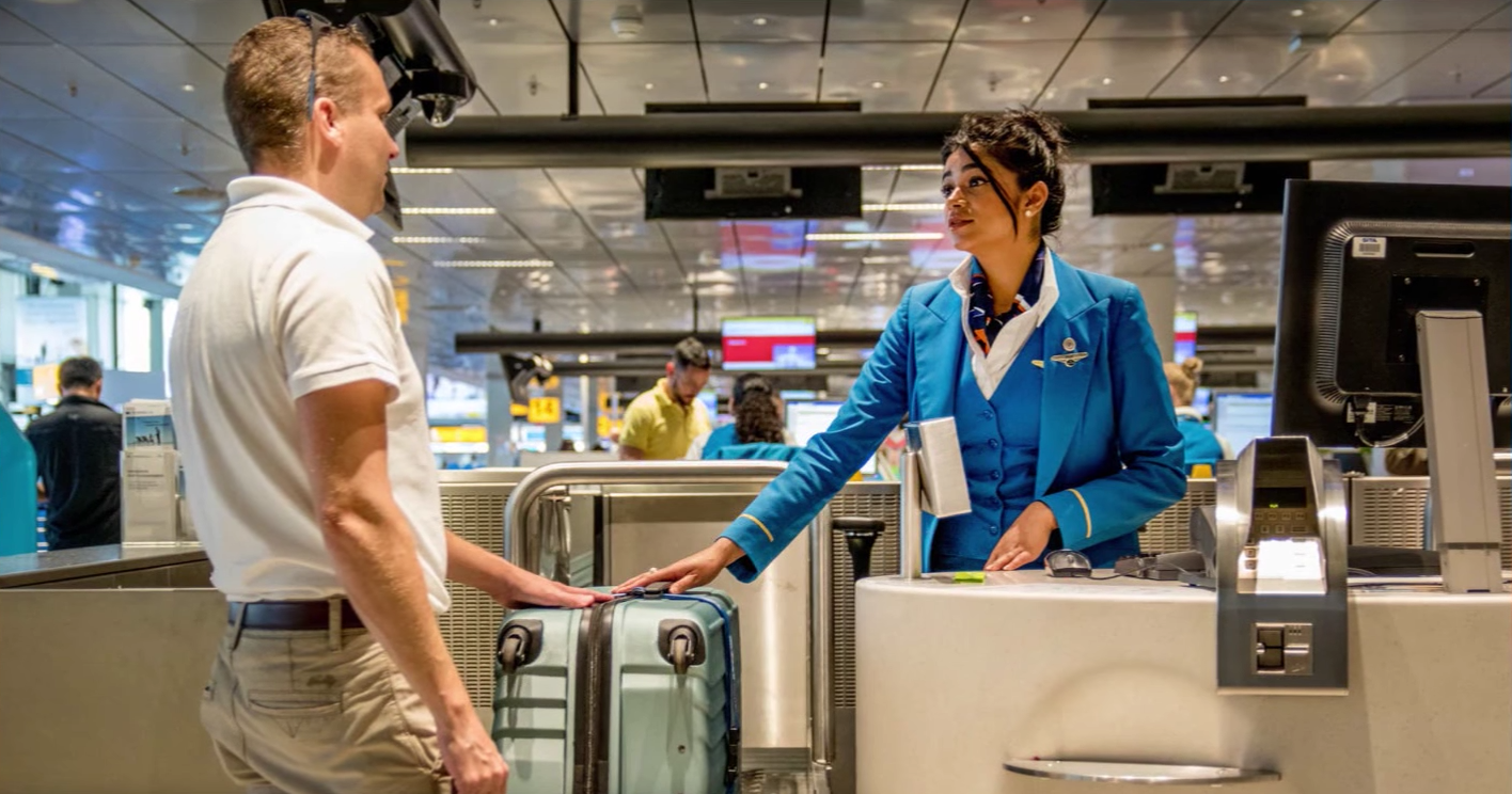 Ein Mann gibt beim Check-in am Flughafen seinen Koffer auf.