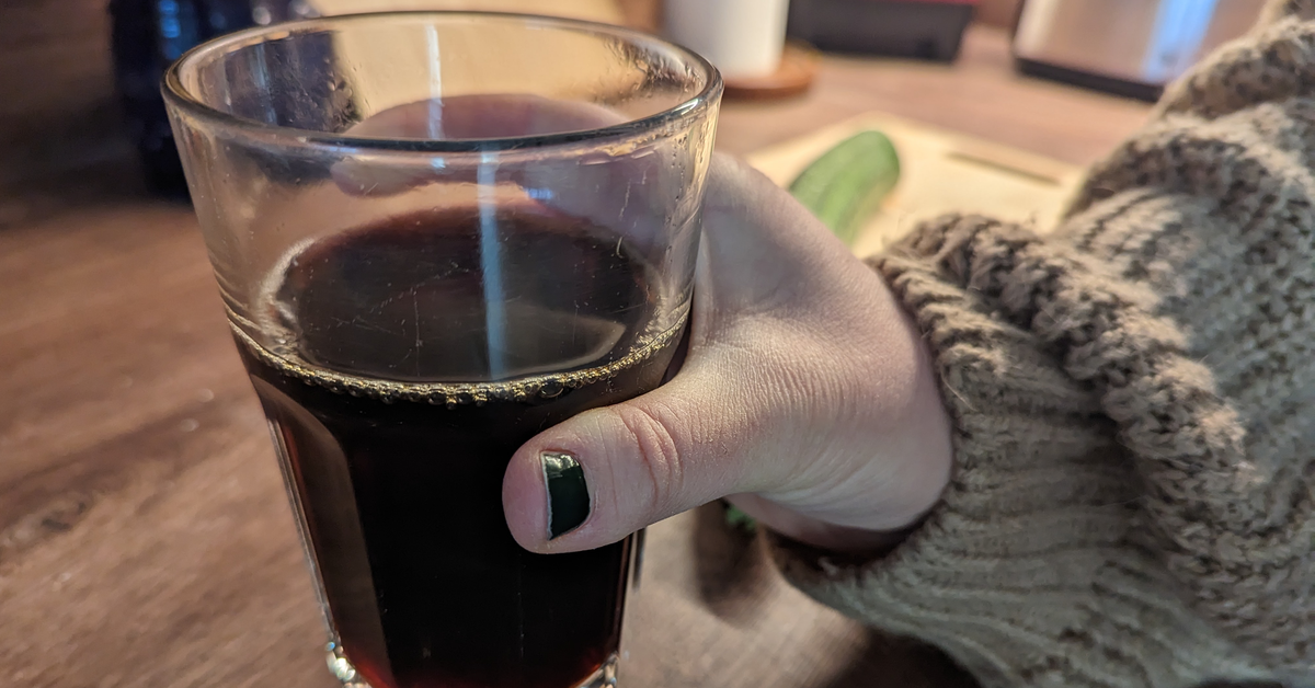 Ein Glas mit Kaffee wird in die Kamera gehalten