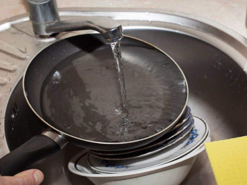 eine beschichtete Pfanne wird mit klarem Wasser ausgespült