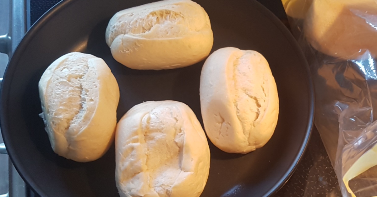 Vier Aufbackbrötchen in einer Pfanne.