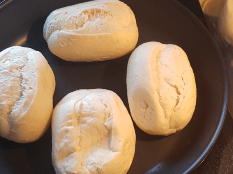 Vier Aufbackbrötchen in einer Pfanne.