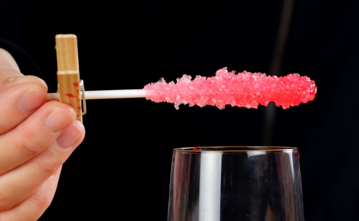 Ein bunter Lolli aus Kandiszucker wird aus einem Glas gezogen.