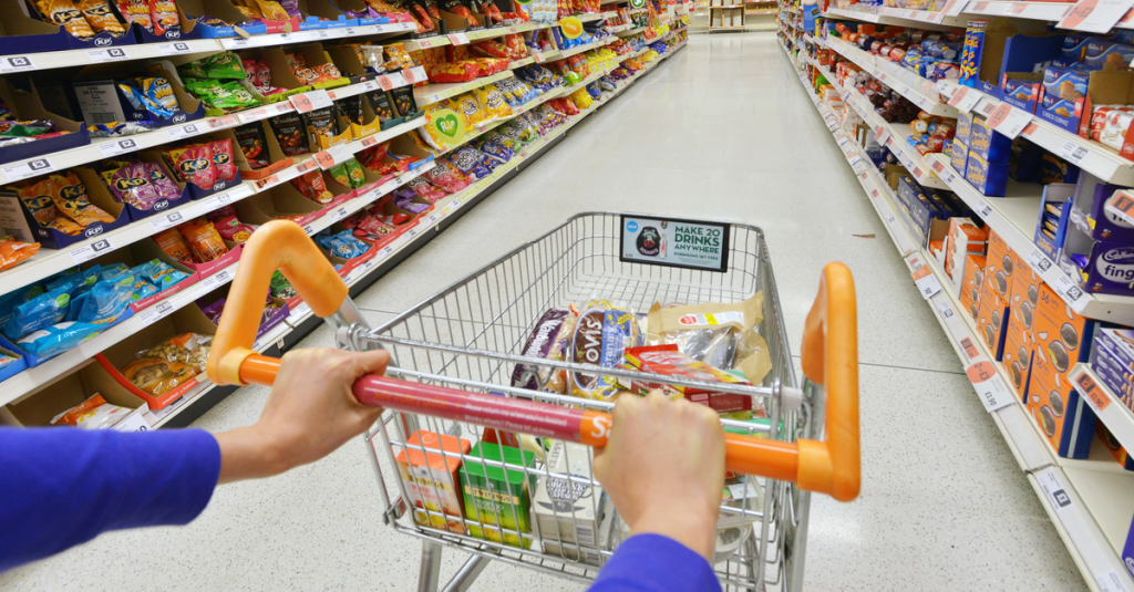 Ein gefüllter Einkaufswagen wird durch den Supermarkt geschoben.