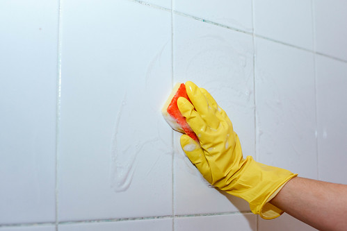 Housemaid cleaning a bathroom tiles