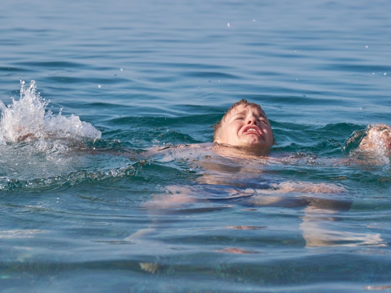 Jugendlicher mit verängstigtem Gesichtsausdruck im Wasser.