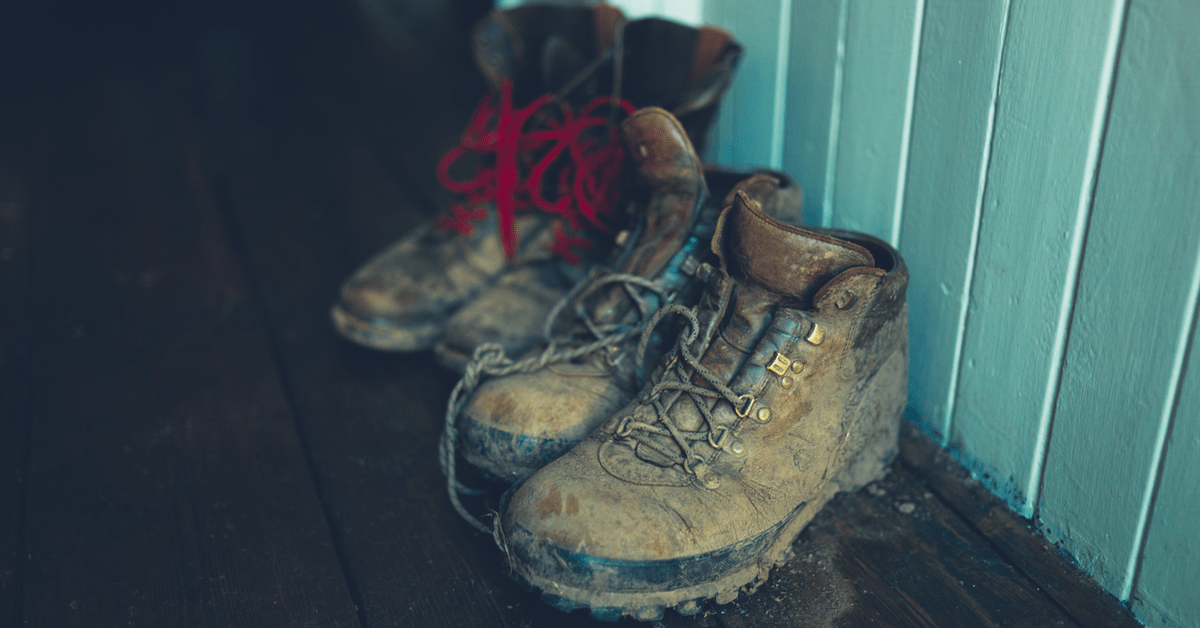 Dreckige Wanderschuhe stehen auf dem Boden.