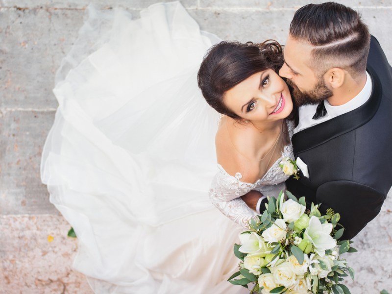 Eine Hochzeitspaar wird von oben fotografiert. Die Braut schaut glücklich nach oben in die Kamera.