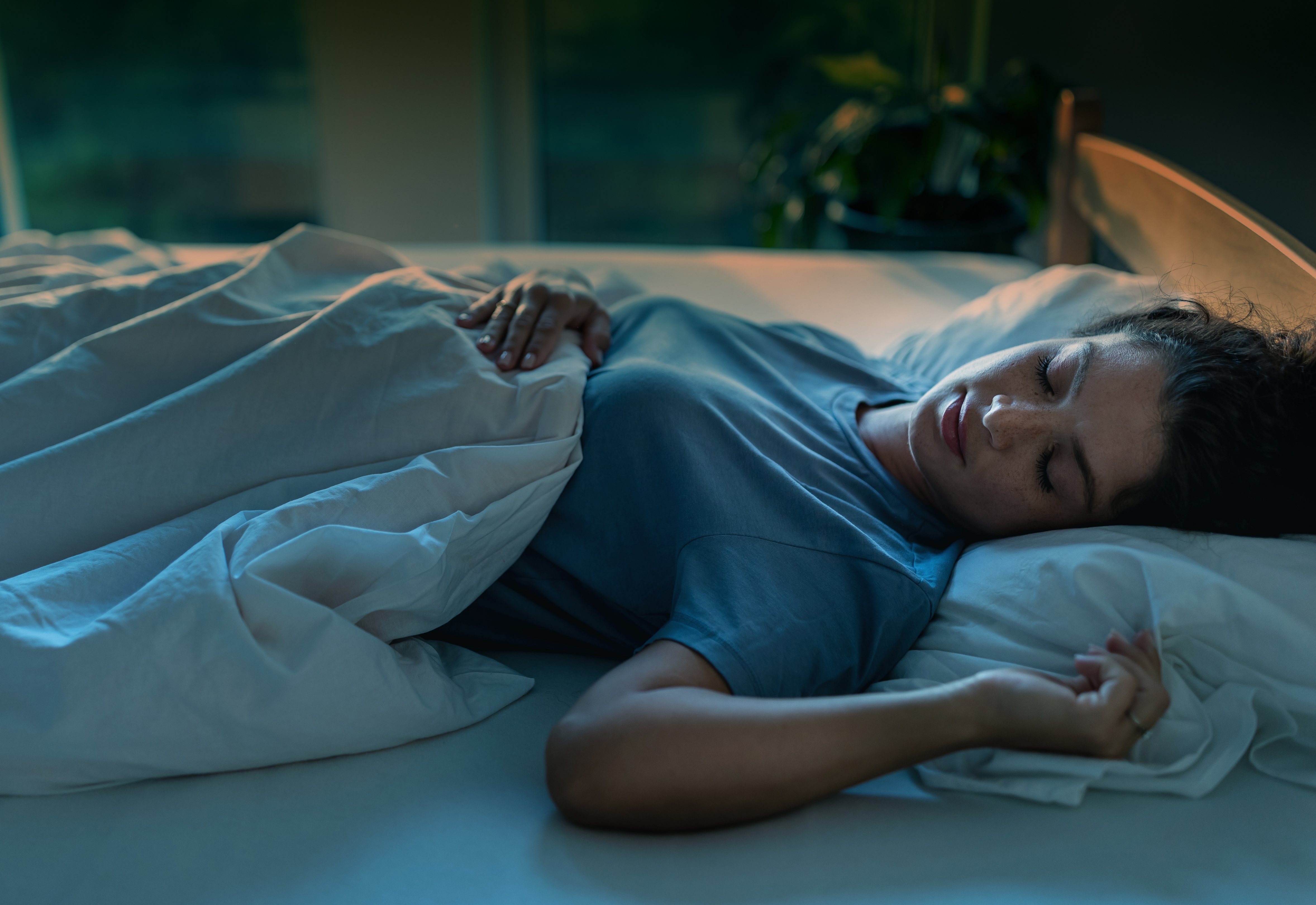 Junge Frau schläft in einem Bett mit Bettwäsche.