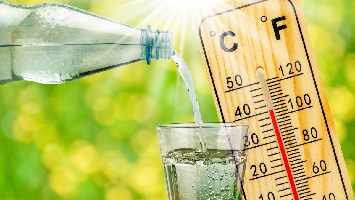 Wasser wird in ein Glas eingeschenkt, daneben ein Thermometer.