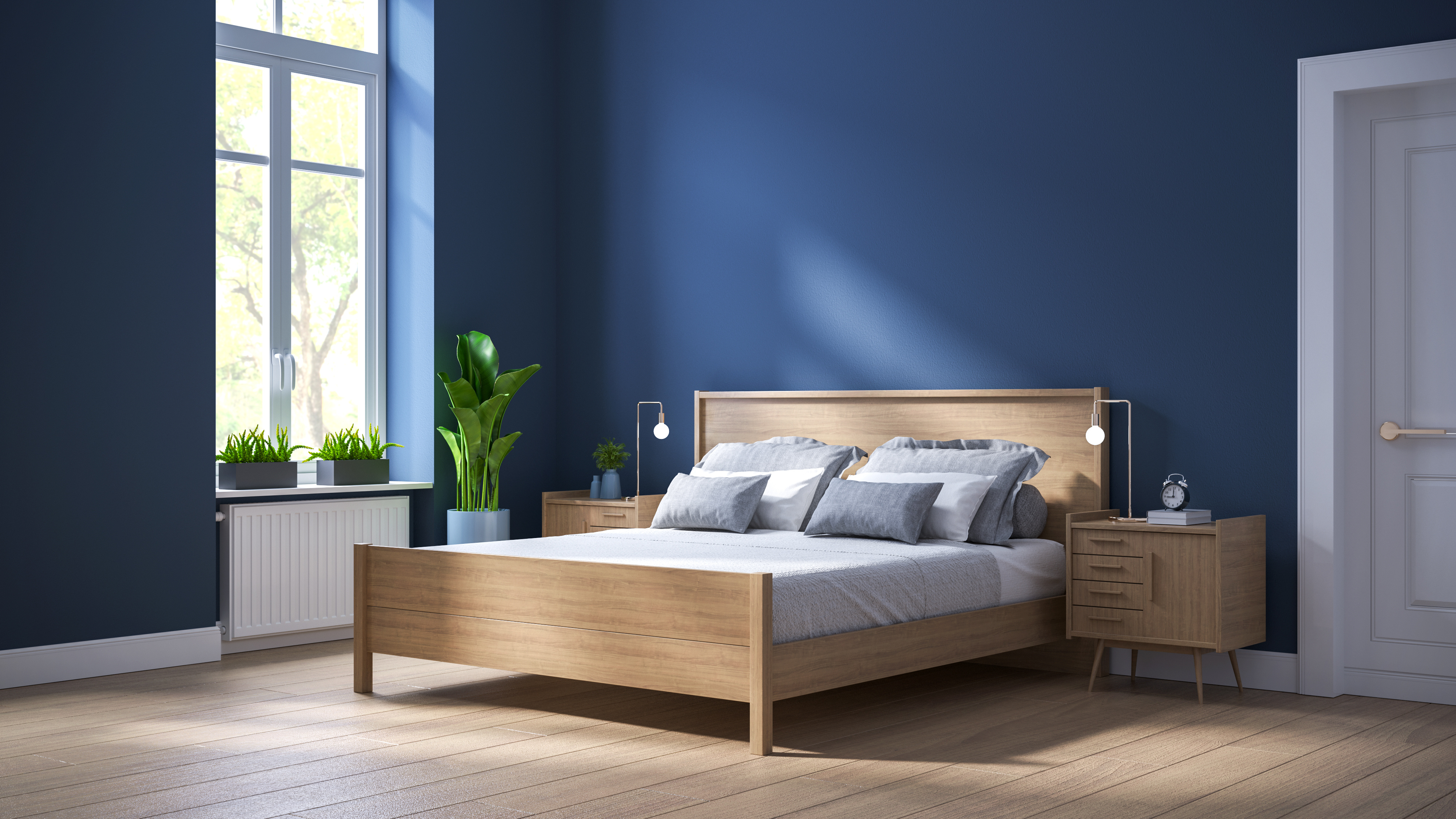 Ein großes Bett steht in einem blauen Schlafzimmer mit großen Fenstern.