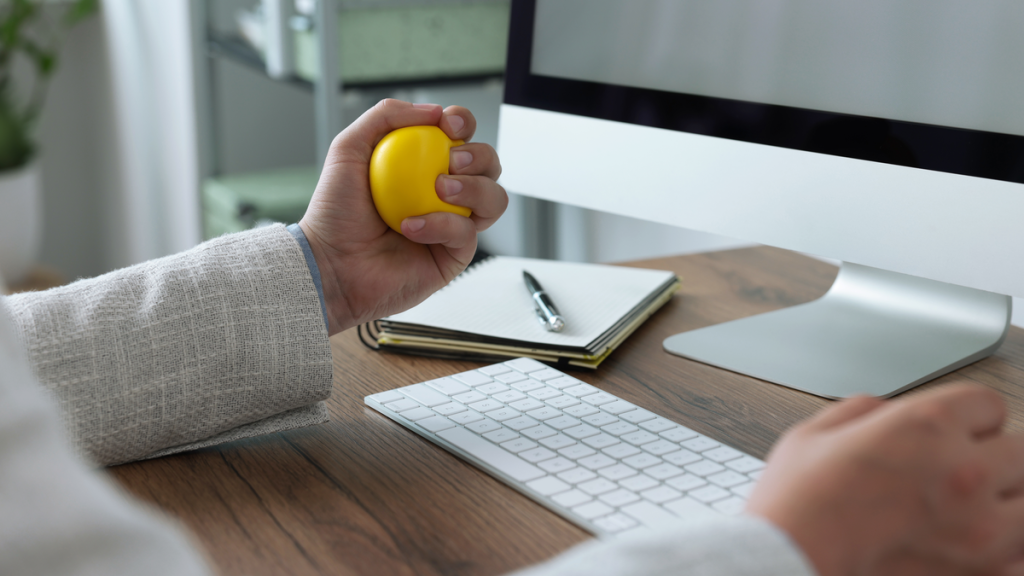 Ein Mann knetet einen gelben Anti-Stress-Ball. 