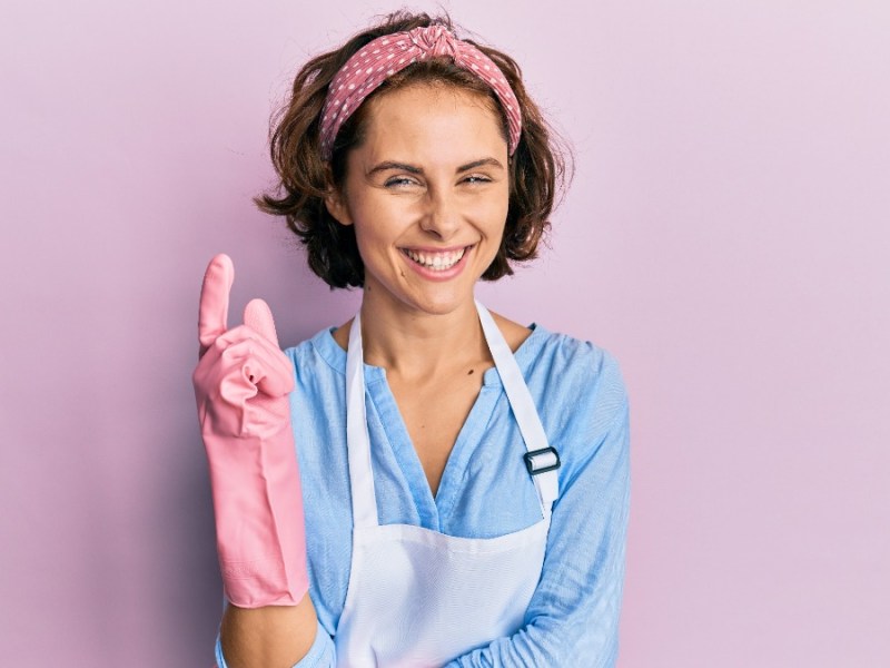 Putzen wie die Profis: eine Frau mit rosa Putzhandschuhen steht vor einer rosa Wand