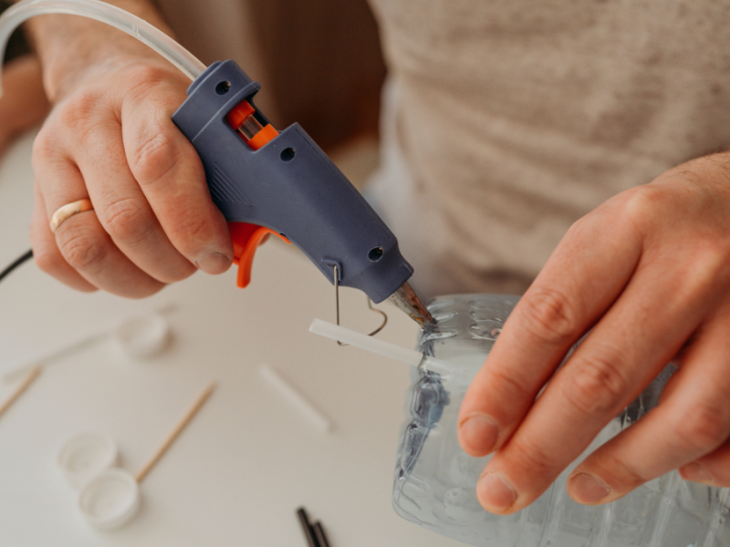 Hände kleben eine Plastikflasche zusammen